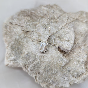 small pearl necklace on a rock and white background.